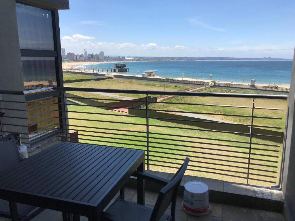 德班Durban Point Waterfront, 505 Quayside 40 Canalquay Rd的阳台配有桌子,享有海滩美景