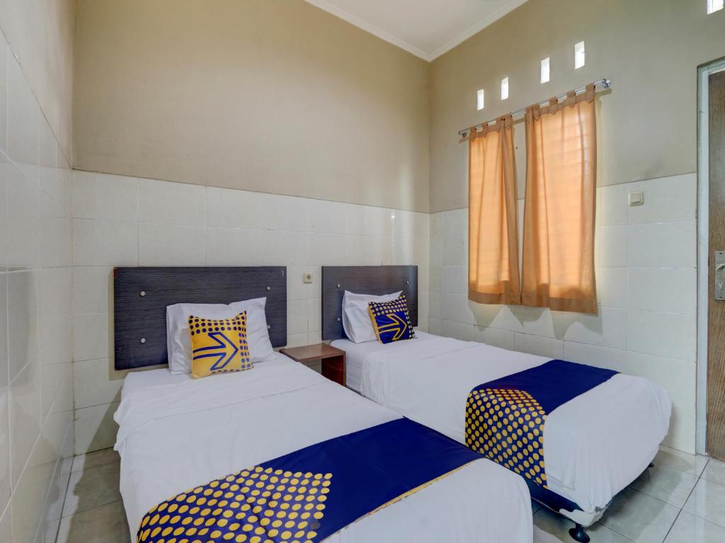 TuntangOYO Life 90159 Puri Asoka Guest House的小型客房 - 带2张床和窗户