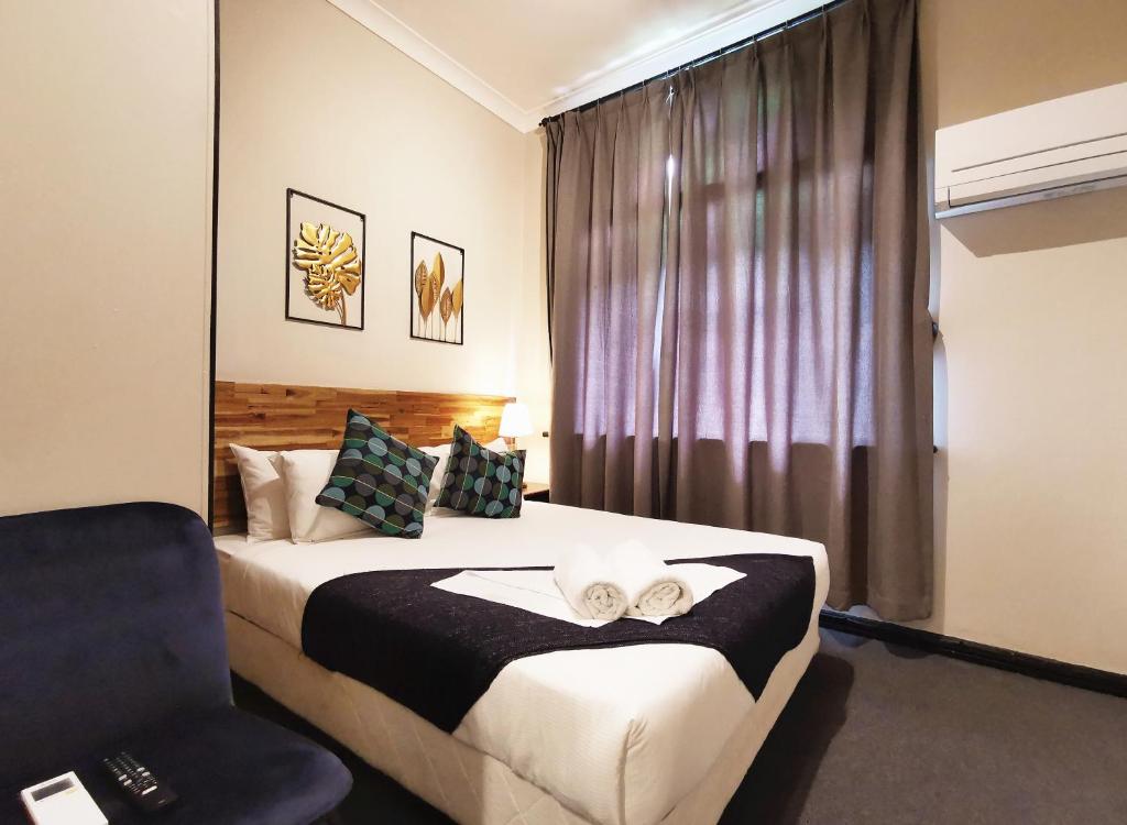 悉尼悉尼克雷西酒店的一间卧室配有一张带椅子的床和一扇窗户