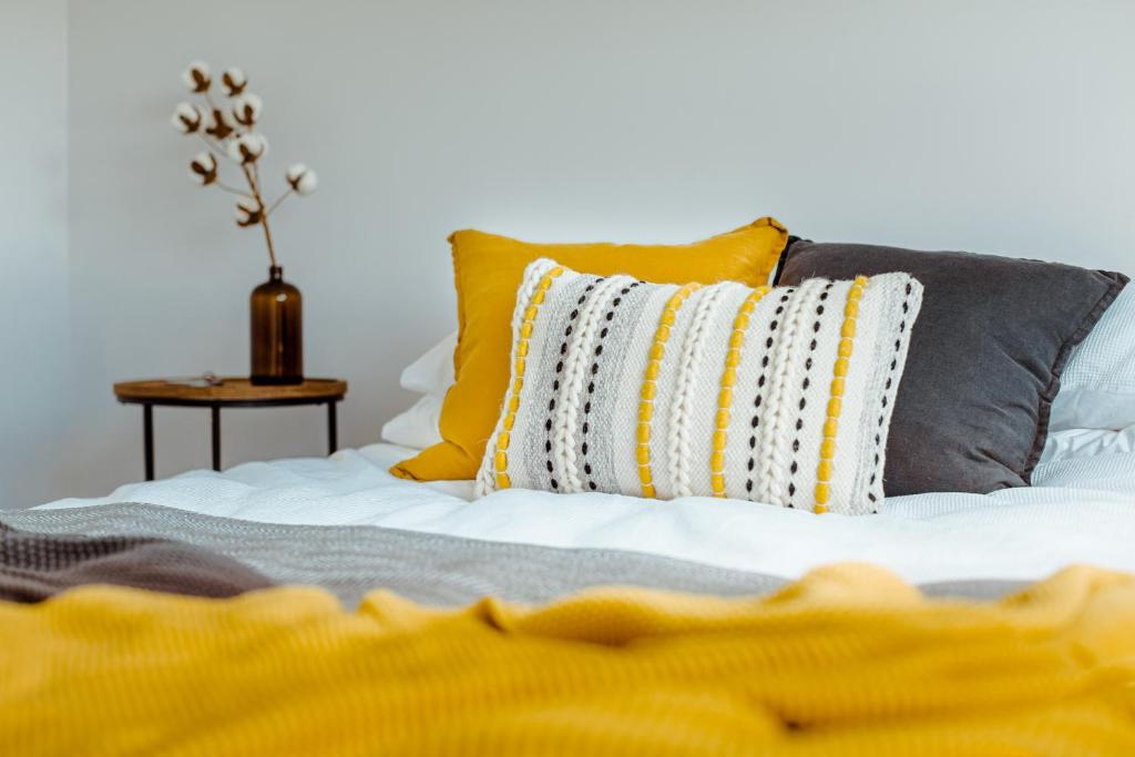 奥阿库尼Mountain Glass - Ohakune Holiday Home的一张带黄色和灰色枕头的床和一张桌子