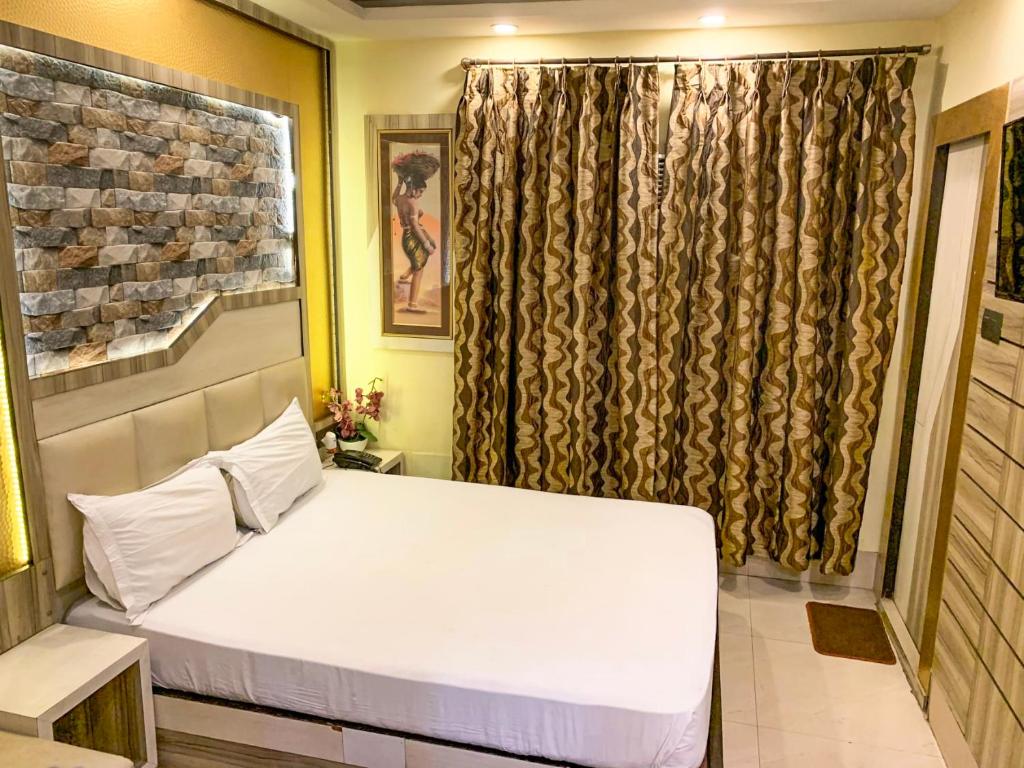 加尔各答Shila International的卧室配有白色的床和窗户。