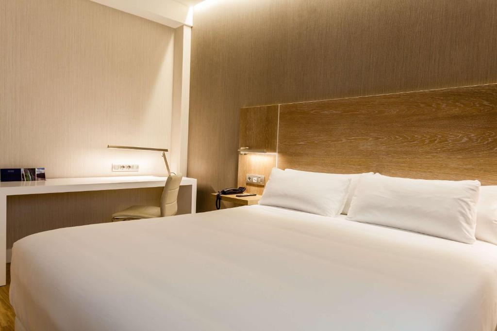 奥维多奥维多普林斯帕多NH酒店的卧室配有一张白色大床和一张书桌