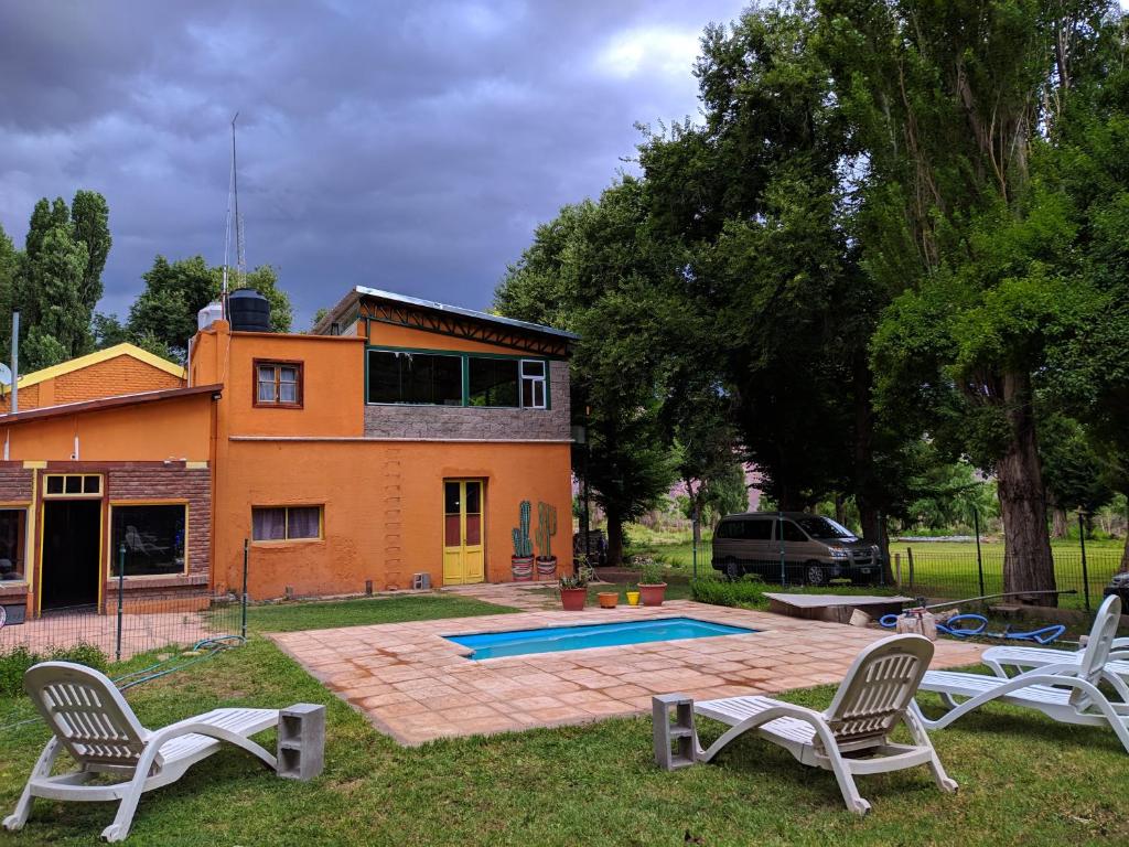 乌斯帕亚塔Hosteria Uspallata的庭院内带游泳池和两把椅子的房子