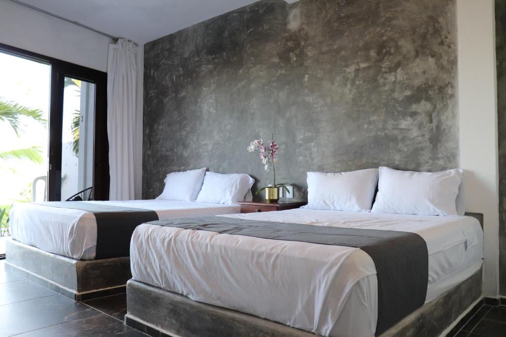La ViguetaLunazul Hotel By Rotamundos的卧室设有两张床铺和混凝土墙