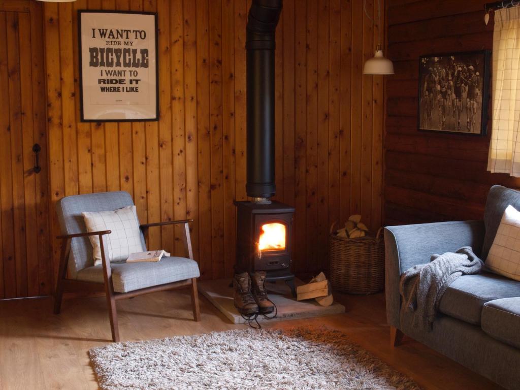 斯特拉西尔Hillside Log cabin, Ardoch Lodge, Strathyre的客厅配有两把椅子和燃木炉