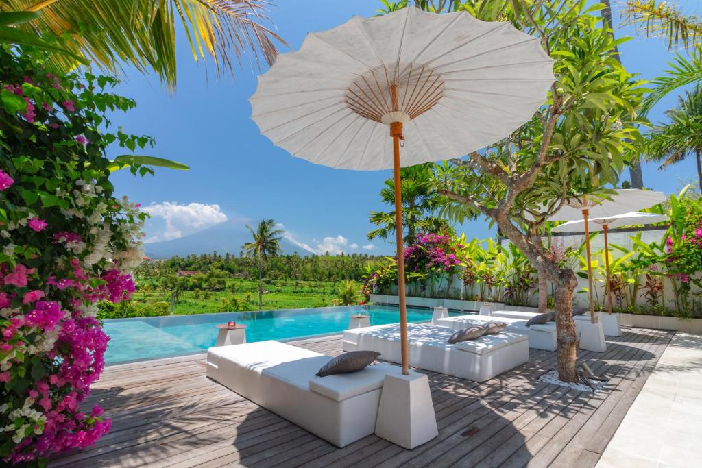 卡朗阿森Villa Palmdream的一个带沙发和遮阳伞的庭院和一个游泳池