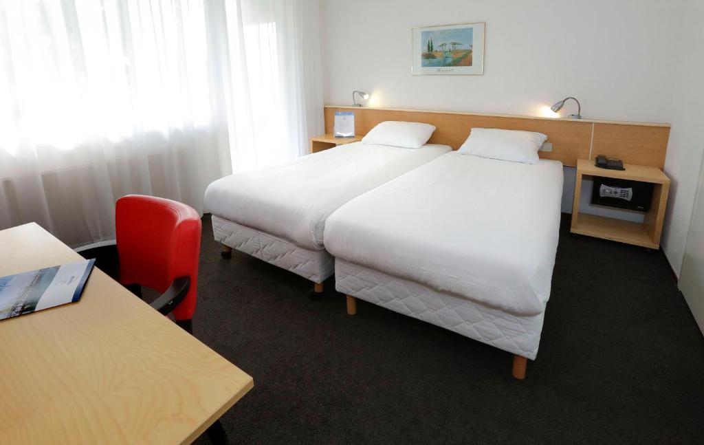 泰尔讷曾City hotel Terneuzen的酒店客房,设有两张床和一张红色椅子
