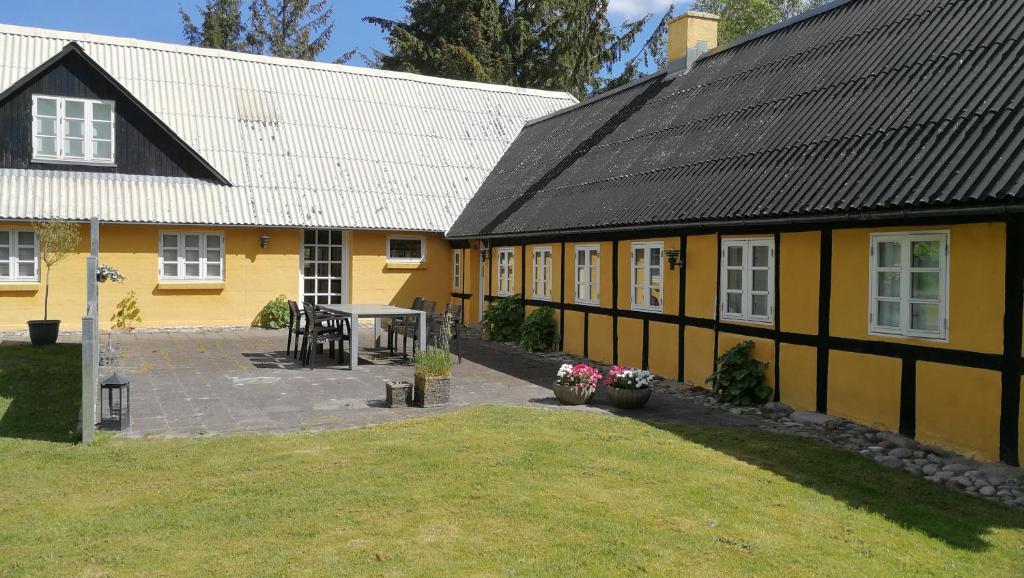 莱斯Fædrelandet Ferielejlighed & Turridning的黄色房子前面有桌子