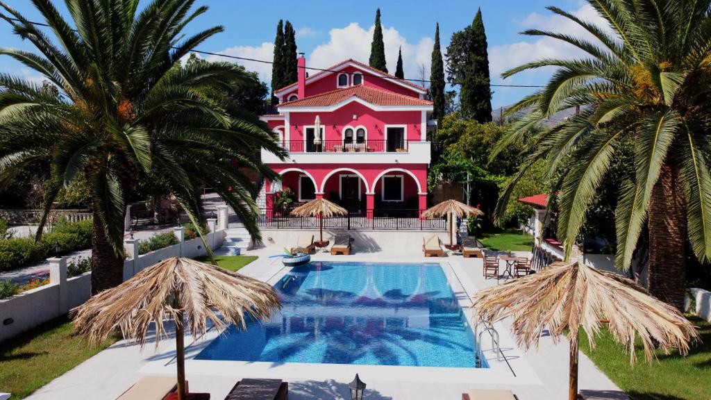 Káto YerakaríonZissis Villa & pool 5min drive to beach的一座大型粉红色房子,设有游泳池和棕榈树