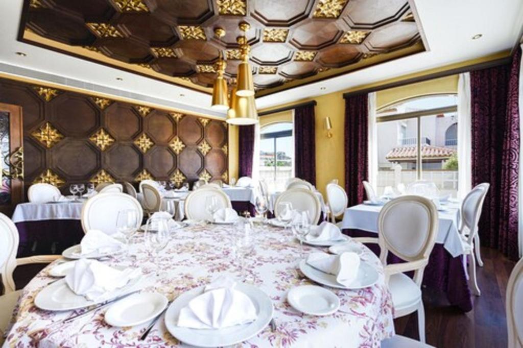 卡拉宏达Hotel El Ancla的一间设有大桌子和白色椅子的用餐室