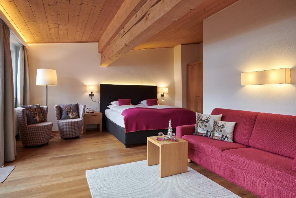 莱赫阿尔贝格Hotel Garni Schneider的一间卧室配有一张床和一张红色的沙发