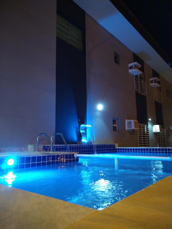 瓜鲁雅Pousada Maré Enseada的夜晚的游泳池,灯光蓝色