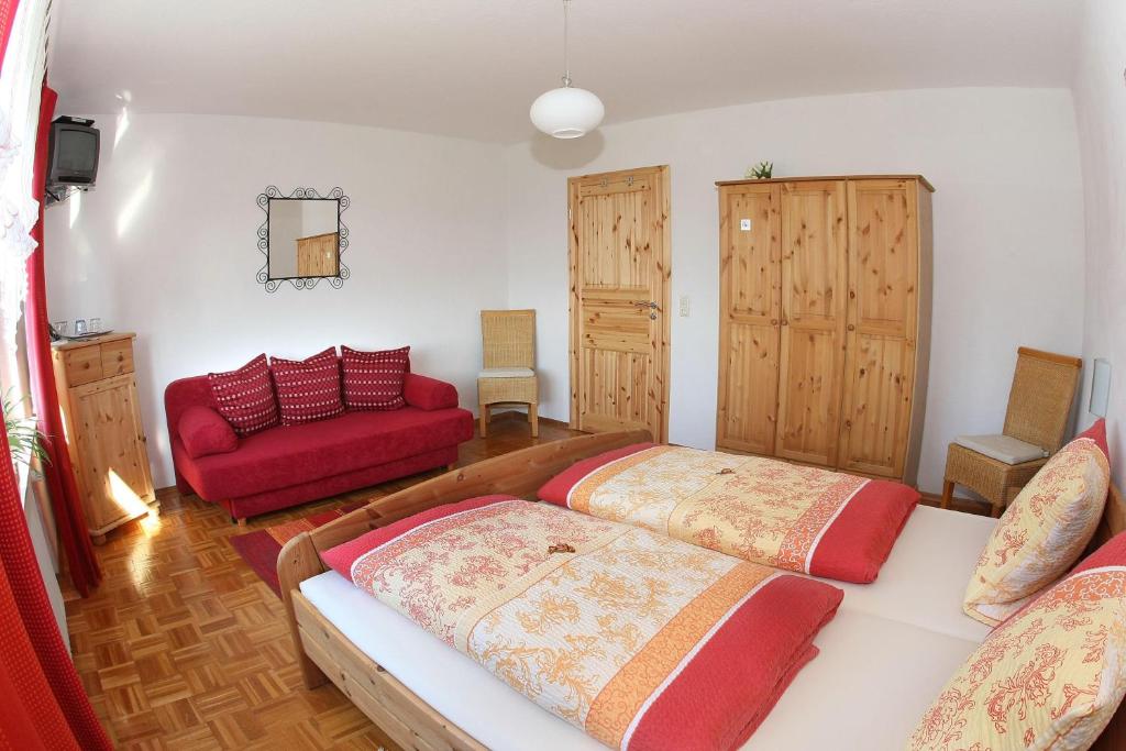 BarweilerGaestehaus-Moeseler的一间卧室配有两张床和一张红色沙发