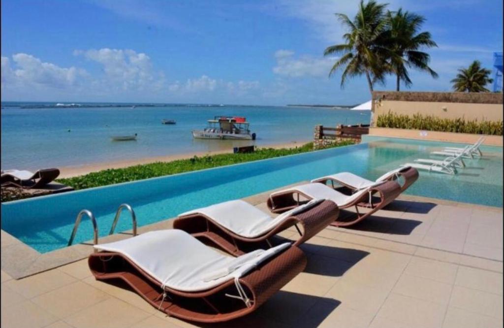 拉巴拉德纳圣米格尔Barra Bali Apartamento 06 - Paraíso à Beira Mar的一组躺椅,坐在游泳池旁