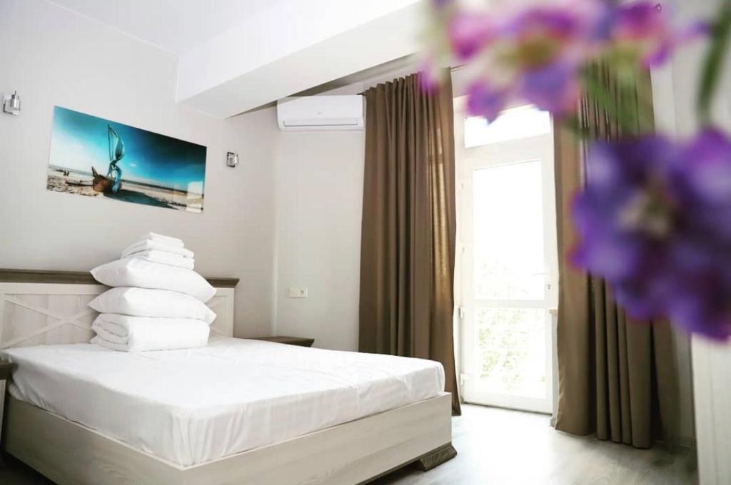 奥恰基夫Foton Hotel & Restaurant的一间卧室配有一张带白色床单的床和一扇窗户。