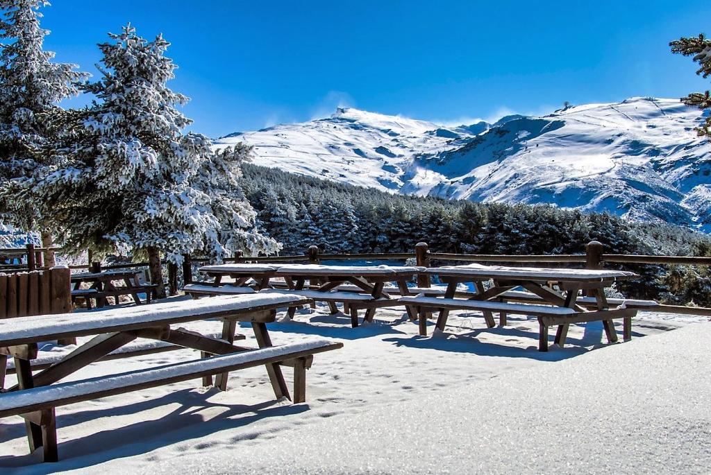 塞拉内华达TODOSIERRANEVADA ZONA BAJA - MONTBLANC VISTAS A LA MONTANA - Junto a los Telecabinas的一群在雪中与山一起野餐桌
