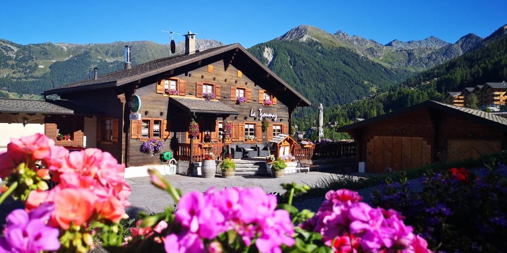 拉茨欧马兹Auberge la Tzoumaz的一座大型的木质建筑,前面有鲜花