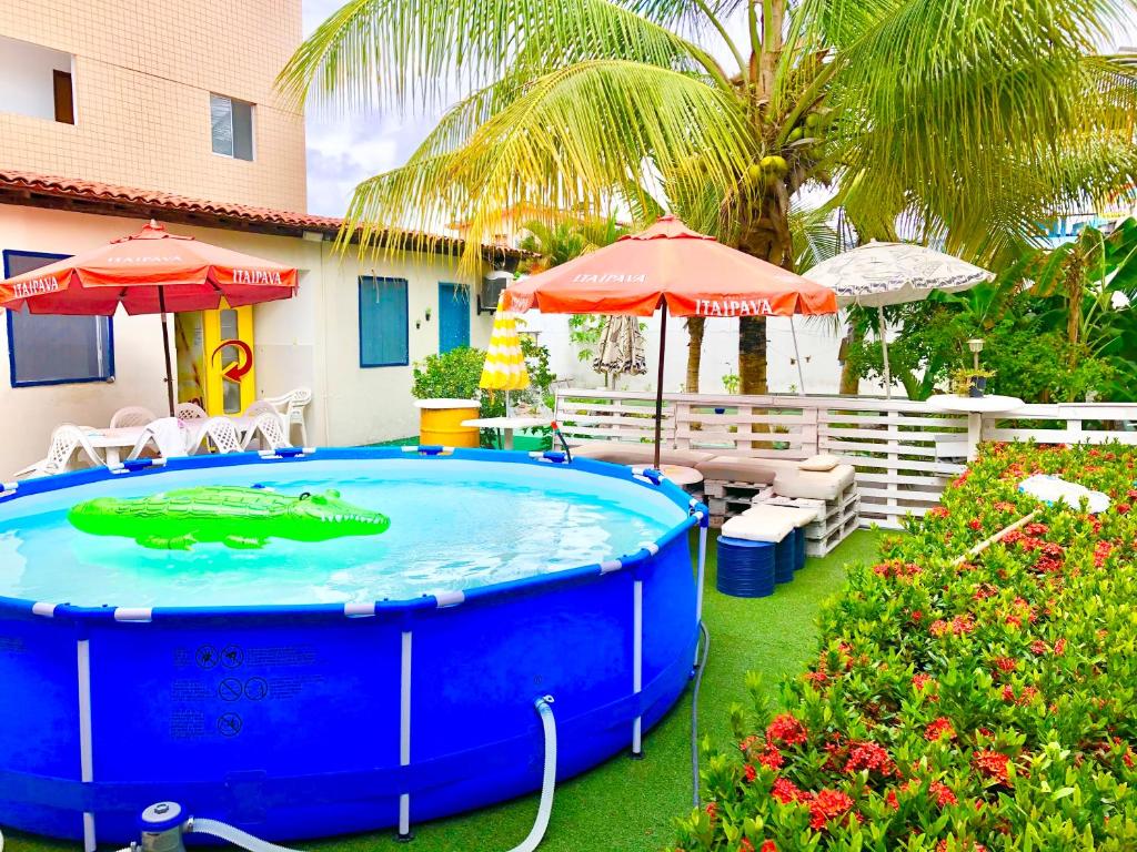 嘎林海斯港Ótima Localização casa, 7 quartos-Porto de Galinhas 900m piscinas naturais的庭院内的热水浴池,配有遮阳伞和鲜花
