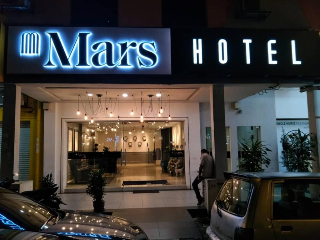 吉隆坡Mars Hotel的男人在男人酒店前行走