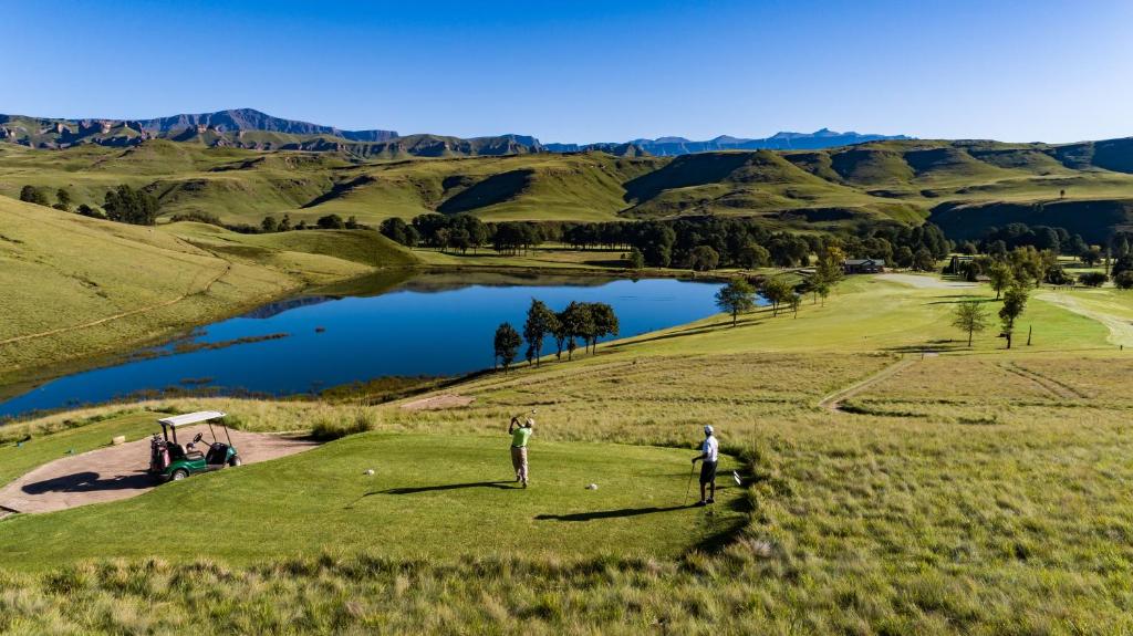 德拉肯斯堡花园Gooderson Drakensberg Gardens Golf & Spa Resort的两人在带湖泊的高尔夫球场打高尔夫