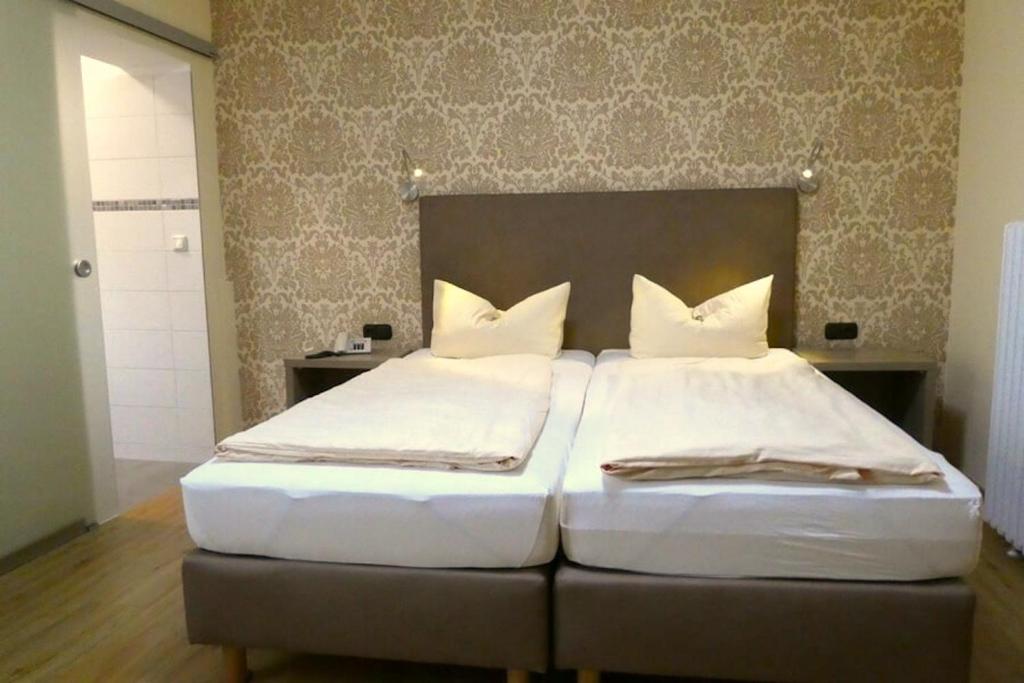 霍夫Hotel Munzert的一间卧室配有两张带白色枕头的床