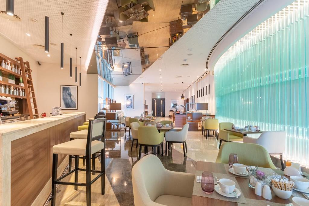 阿布扎比Grand Millennium Al Wahda Hotel and Executive Apartments Abu Dhabi的一间带桌椅的餐厅和一间酒吧
