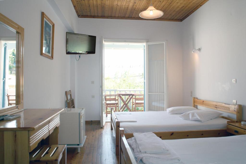 阿约斯尼奇塔斯Elena Rooms的一间卧室设有两张床,墙上配有电视。