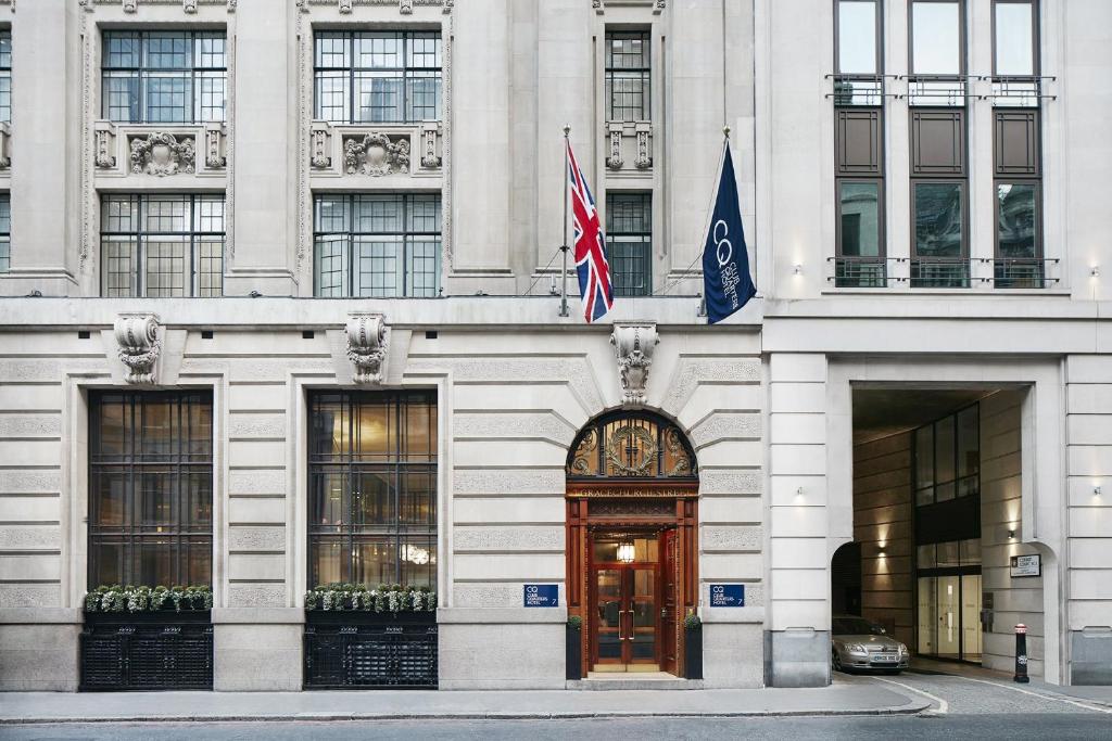 伦敦Club Quarters Hotel London City, London的前面有两面旗帜的建筑