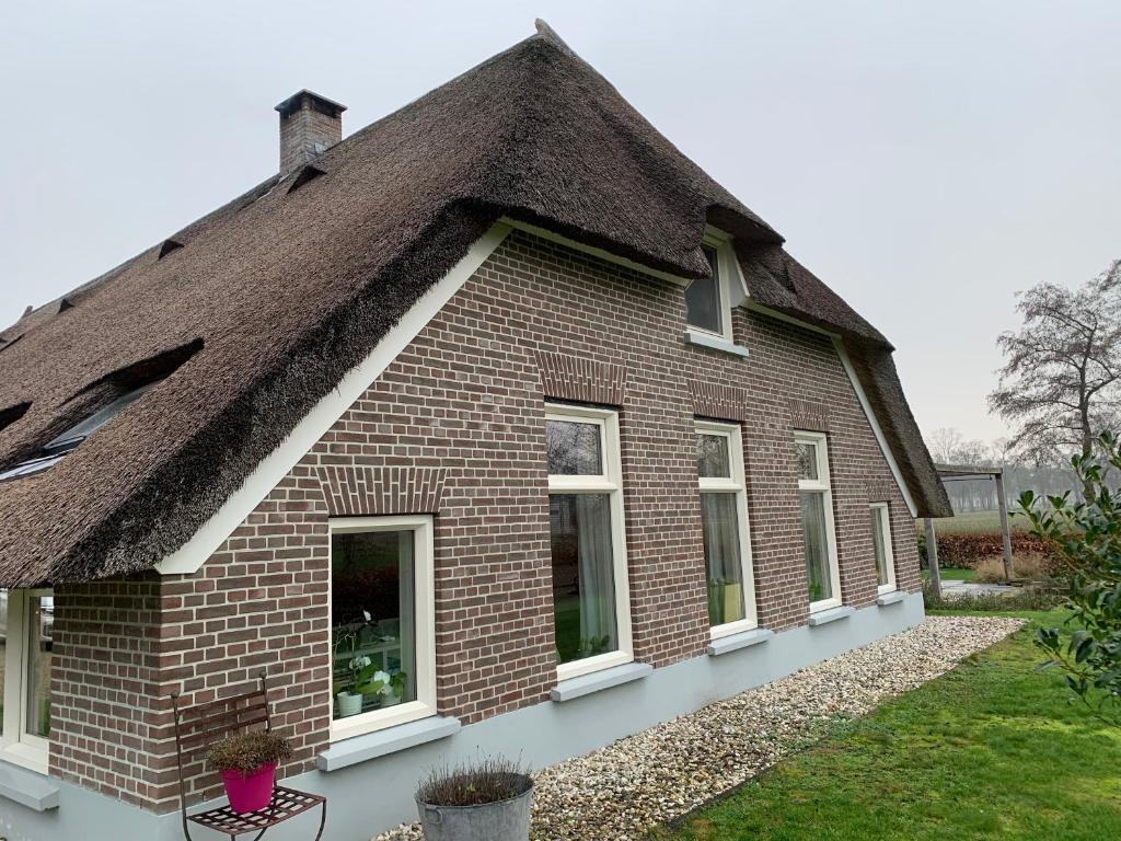 NieuwleusenDe Boerderij - Buitenplaats Ruitenveen, privé的一座带茅草屋顶的老砖屋