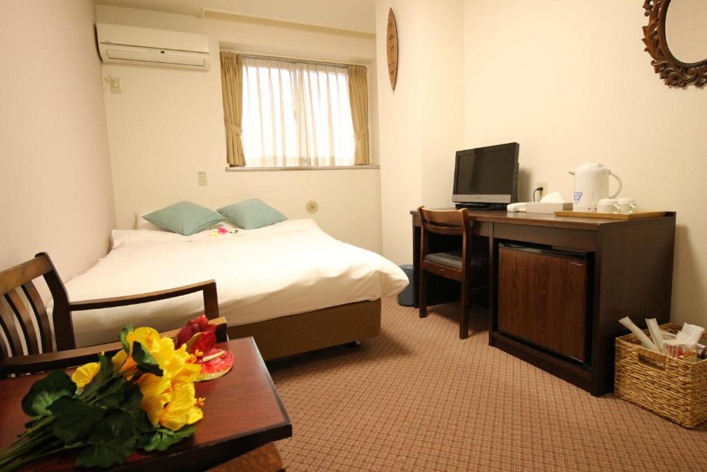 东京Okubo Hotel Hawaii的酒店客房配有一张床、一张书桌和一台电视。