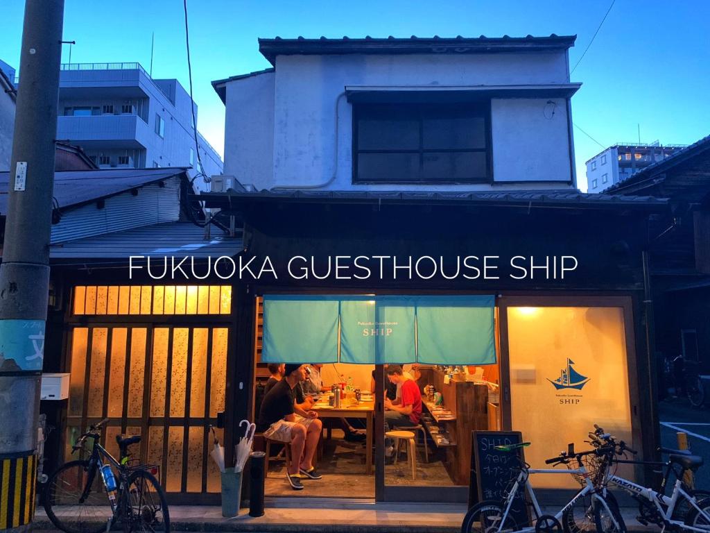 福冈Fukuoka Guesthouse SHIP的餐馆,人们坐在窗边的桌子上