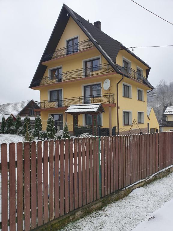 PoniceNoclegi w gorcach的前面有栅栏的黄色房子