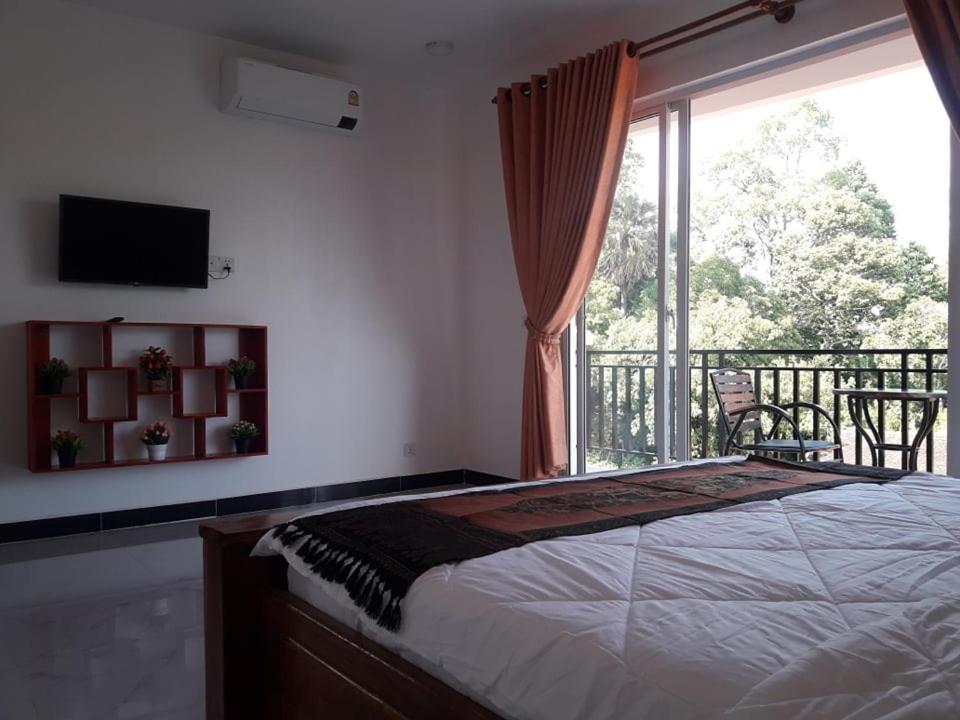 暹粒Khun Pich Apartments的一间卧室配有一张床,阳台设有窗户