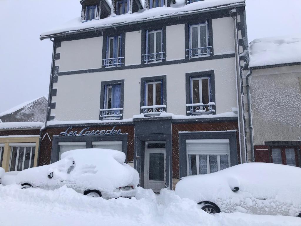 勒蒙多尔Les cascades的前方有汽车停放的积雪覆盖的建筑