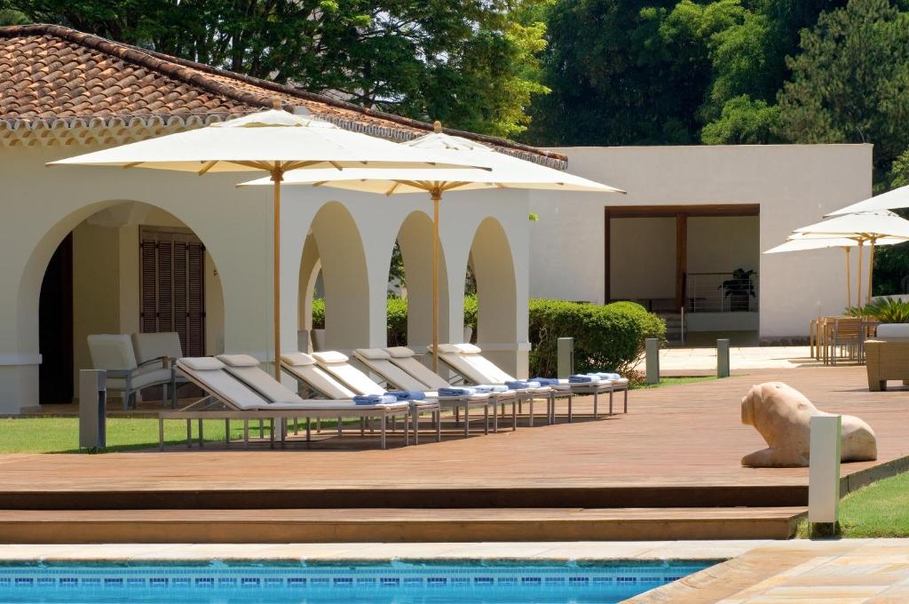圣若昂-德雷园山酒店与高尔夫度假村的一组躺椅,在游泳池畔摆放着遮阳伞