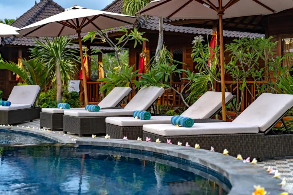 蓝梦岛Karang Mas Villa Nusa Lembongan的度假酒店的游泳池配有躺椅和遮阳伞