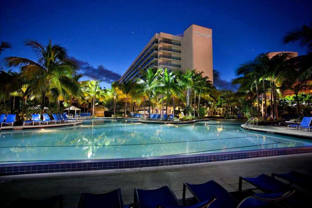 好莱坞好莱坞海滩希尔顿逸林度假酒店的一个带蓝色椅子的大型游泳池和一间酒店