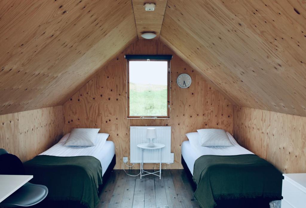 Sandgerði爱思戴小屋酒店的木间设有两张床,设有窗户