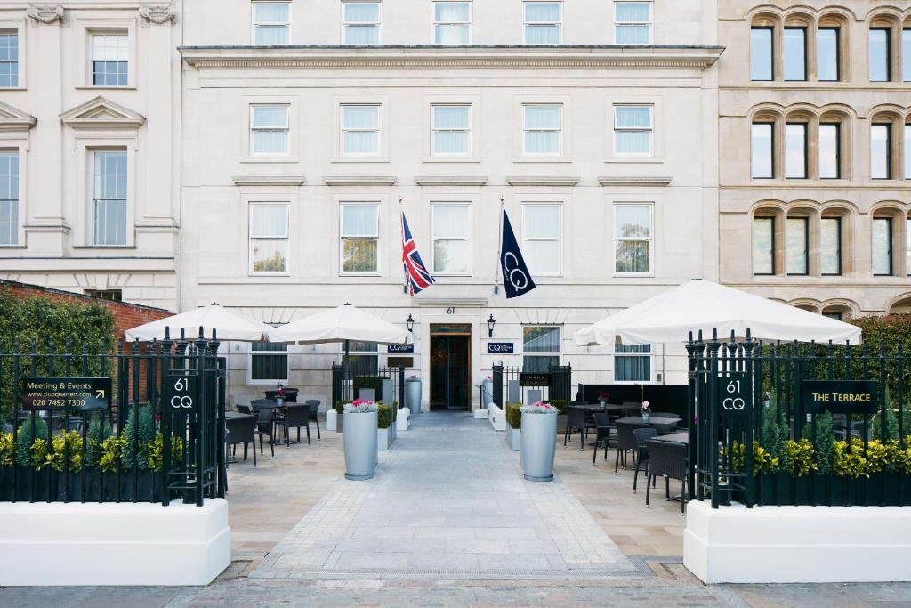 伦敦Club Quarters Hotel Covent Garden Holborn, London的前面有桌子和伞的建筑