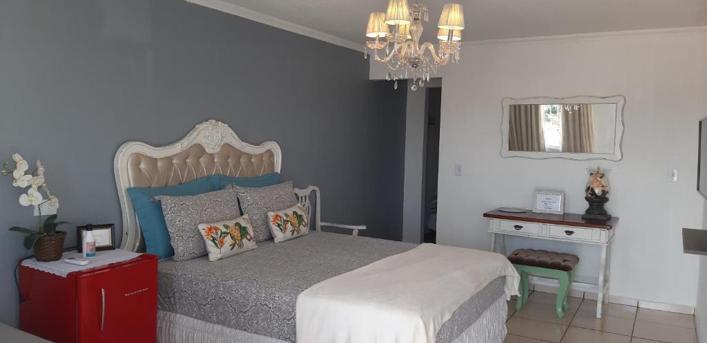 伊瓜苏Pousada Cris Garden Bed&Breakfast的一间卧室配有一张床、一张桌子和一个吊灯。
