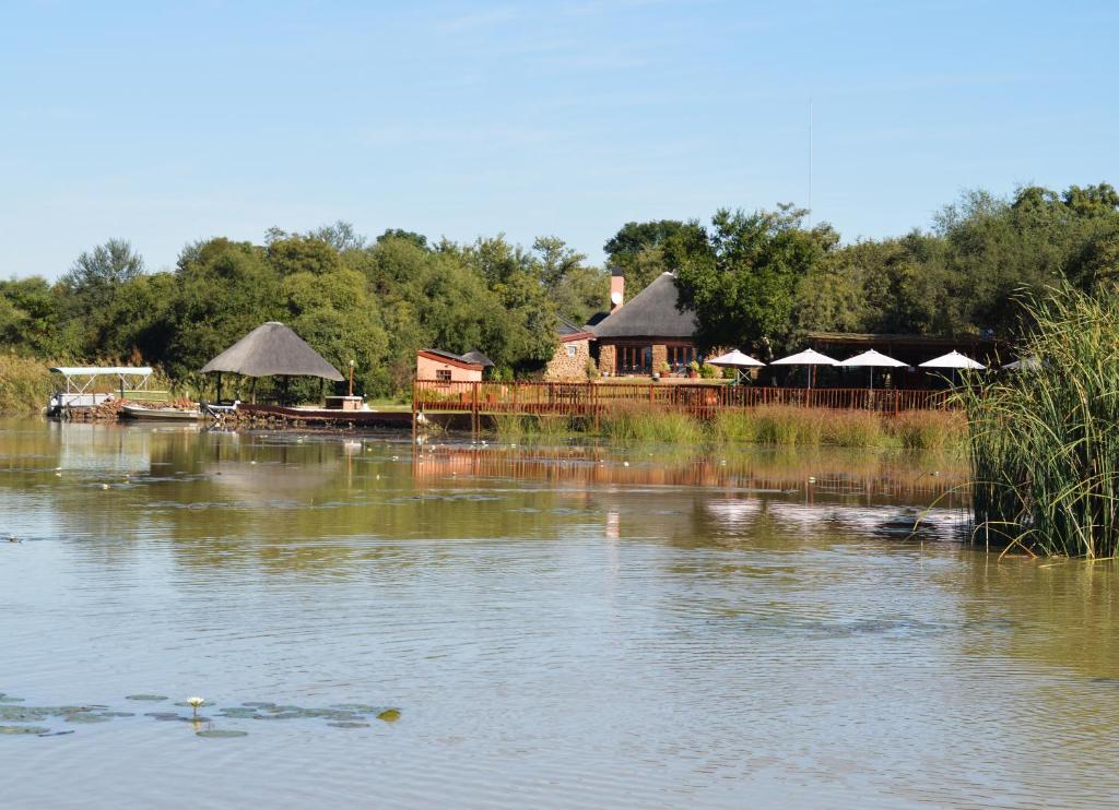 哈博罗内Crocodile Pools Resort的一座拥有众多建筑和树木的大湖