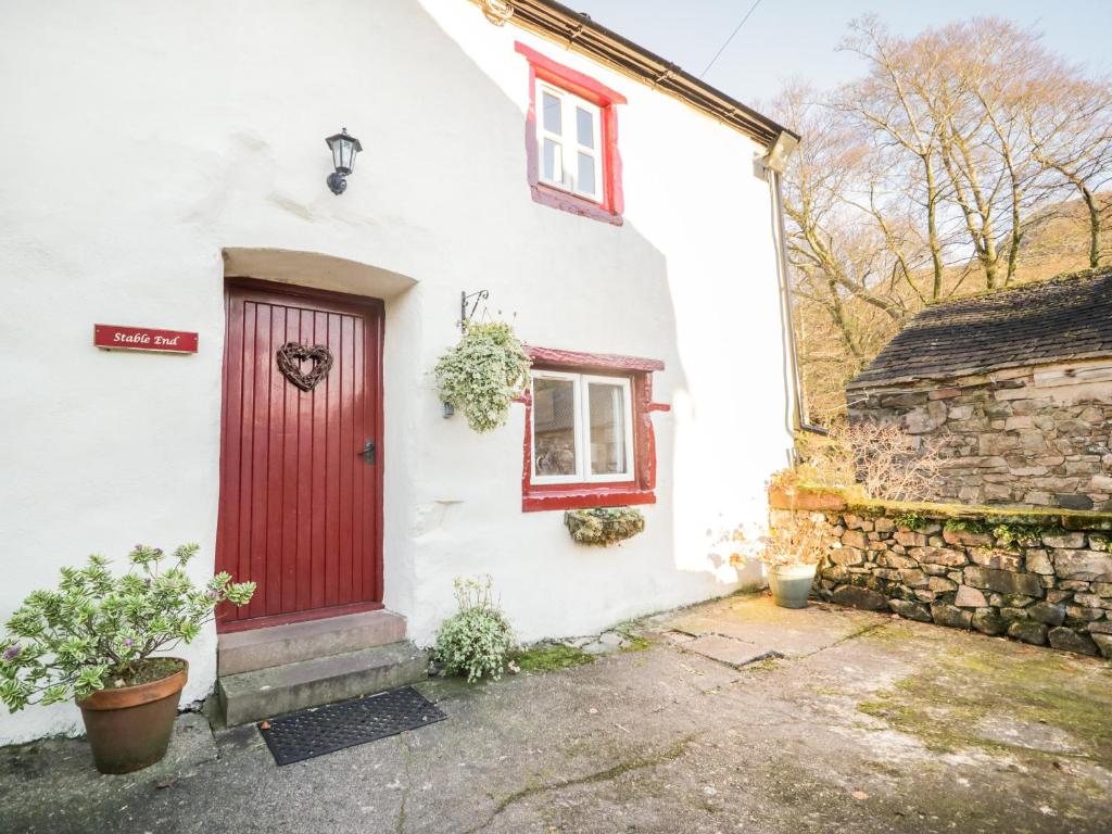 瓦斯代尔下城Stable End Cottage的白色的房子,有红色的门和石墙