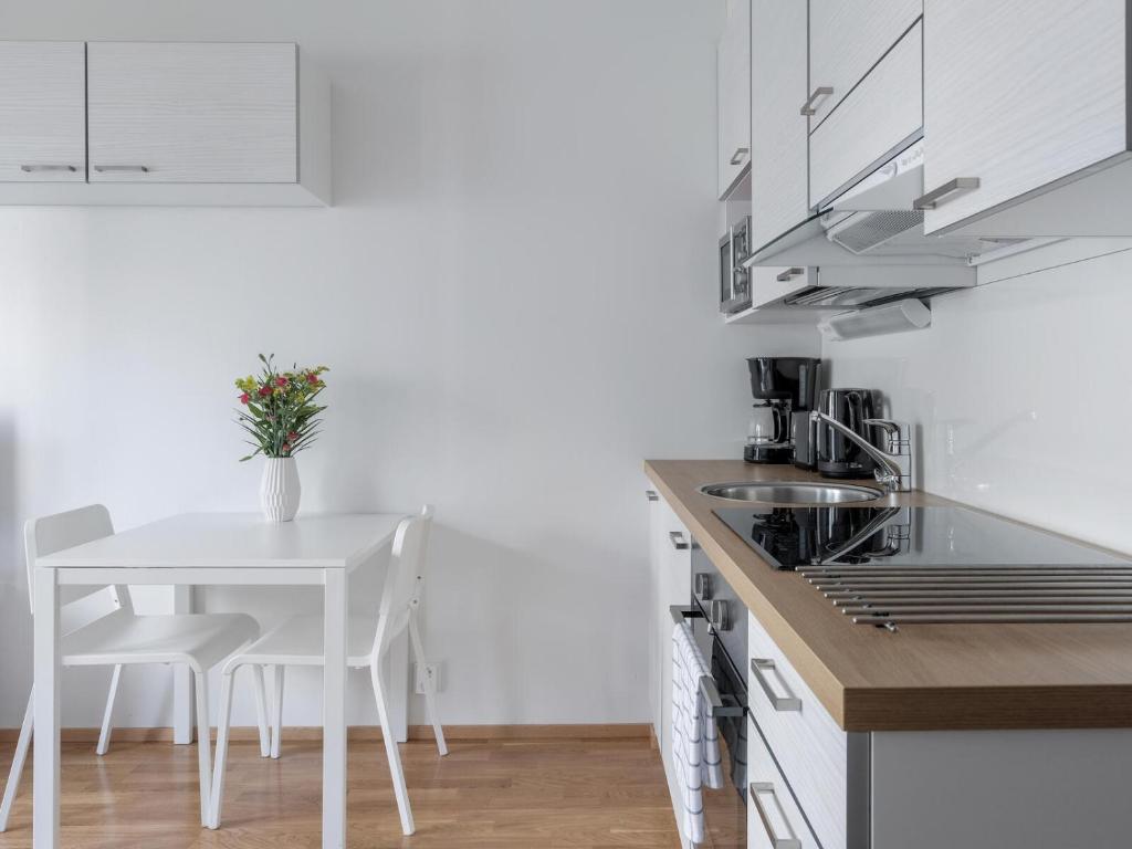 约恩苏Kotimaailma Apartments Joensuu - Koulukatu 21的厨房配有桌子和白色的桌椅