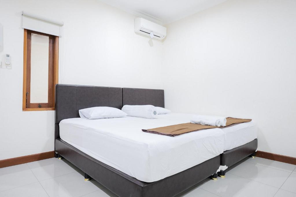 雅加达wisma delapan Mitra RedDoorz的一间卧室配有一张带白色床单的床和一扇窗户。
