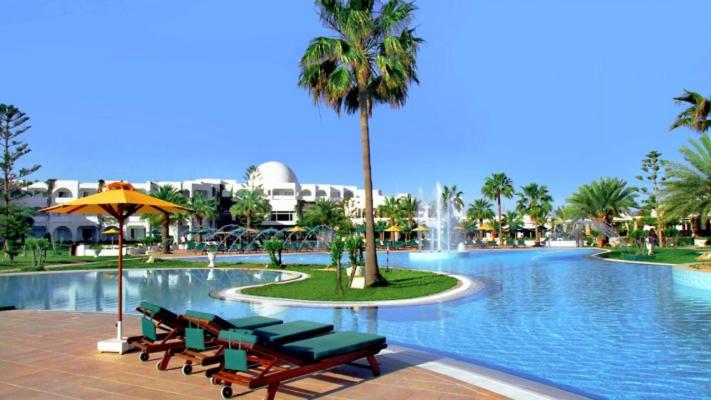 米多恩Djerba Plaza Thalasso & Spa的一个带椅子的游泳池、棕榈树和喷泉