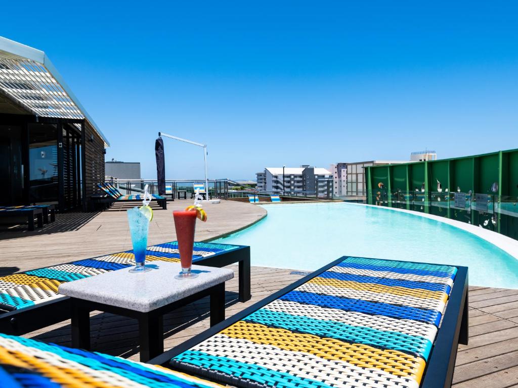 德班aha Gateway Hotel Umhlanga的游泳池畔的两把椅子和一张桌子