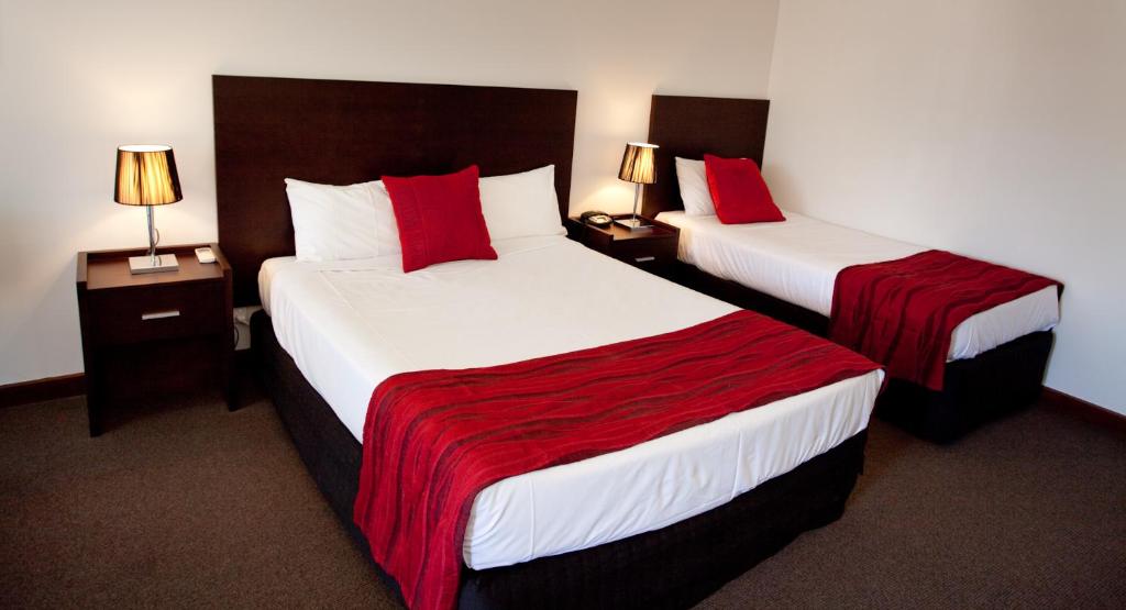 伊丘卡伊丘卡港美居酒店的两张位于酒店客房的床铺,配有红色枕头