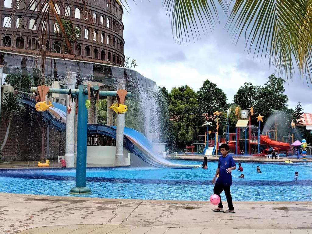 马六甲Melaka BY LG Water Themepark & Resort By GGM的在一个水上公园前玩球的女孩