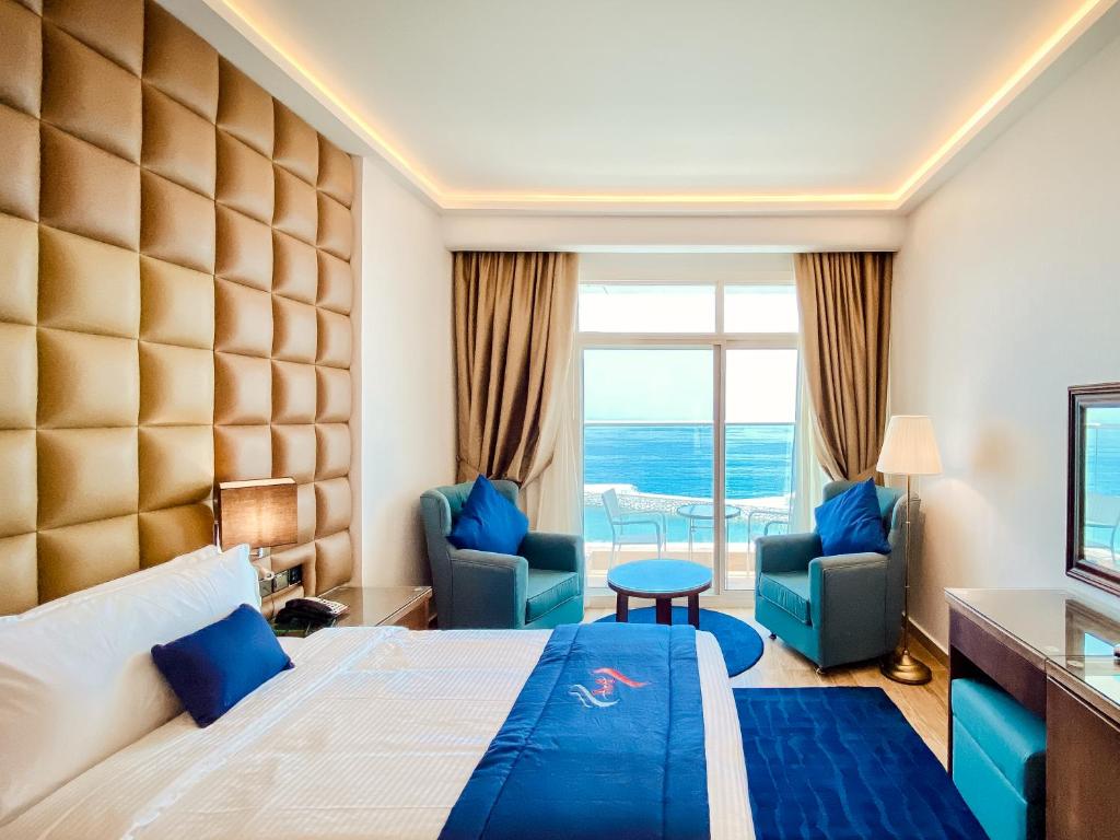 迪巴Mirage Bab Al Bahr Beach Hotel的酒店客房,配有一张床和两把椅子