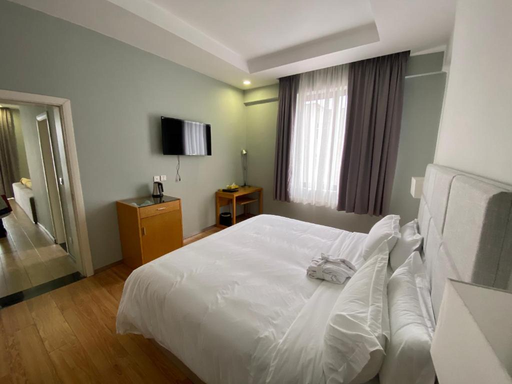 亚的斯亚贝巴Cot Hotel (ቆጥ ሆቴል)的卧室配有白色的床和电视。